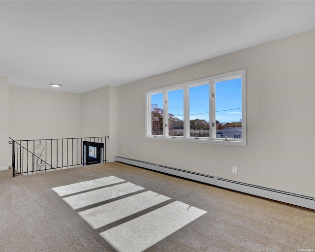 carpeted spare room with a baseboard heating unit