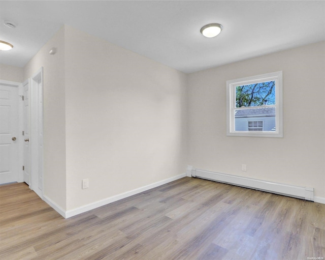 unfurnished room with a baseboard radiator and light wood-type flooring