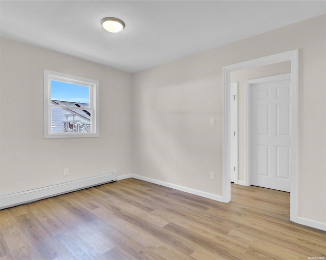 unfurnished room featuring a baseboard heating unit and light wood-type flooring