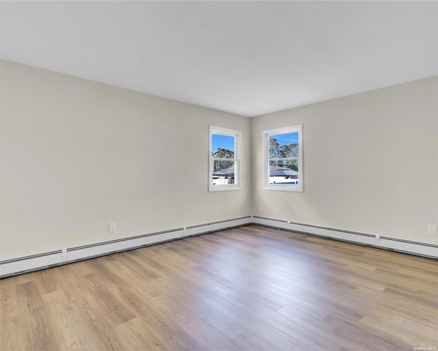 unfurnished room featuring light wood-type flooring and a baseboard heating unit