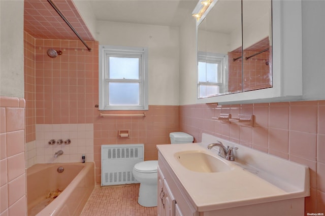 full bathroom with vanity, radiator, tiled shower / bath, toilet, and tile walls