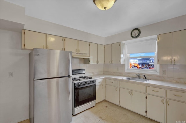 kitchen with cream cabinetry, stainless steel fridge, and white range with gas cooktop