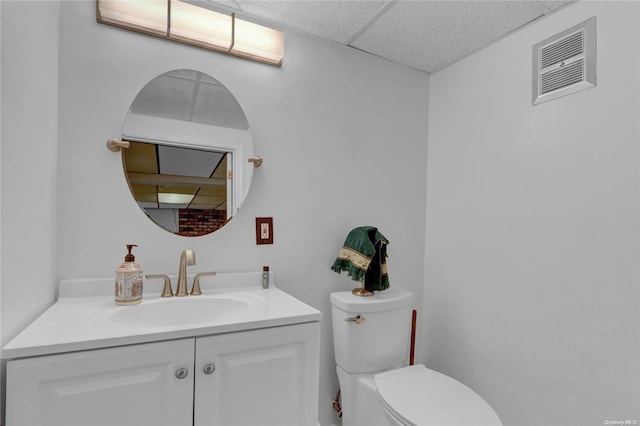 bathroom featuring vanity, toilet, and a drop ceiling