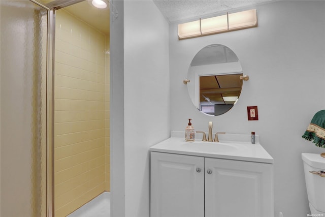 bathroom featuring a tile shower, vanity, and toilet