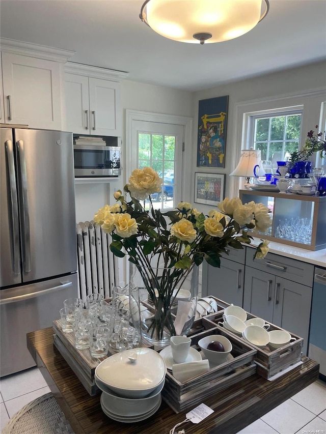 kitchen featuring radiator heating unit, stainless steel appliances, white cabinets, gray cabinets, and light tile patterned flooring