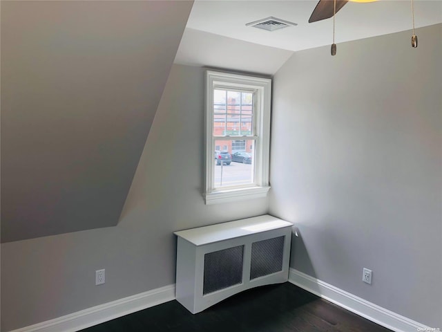 additional living space with radiator heating unit, dark hardwood / wood-style floors, vaulted ceiling, and ceiling fan