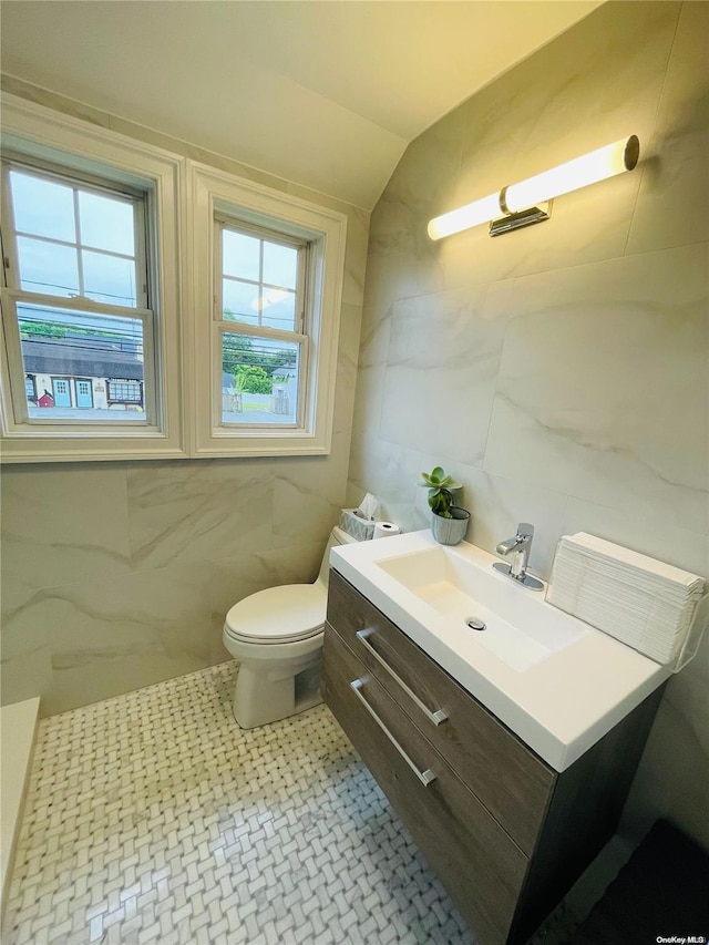 bathroom featuring vanity, toilet, tile walls, and vaulted ceiling