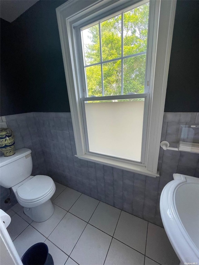 bathroom featuring tile patterned flooring, toilet, and tile walls