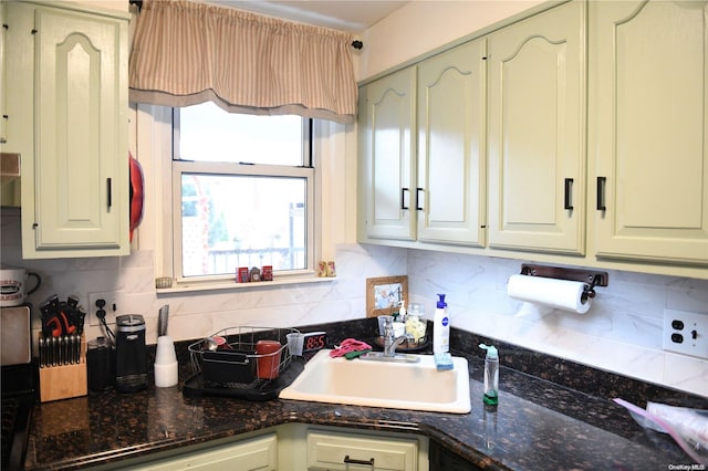 kitchen with dark stone counters, sink, and backsplash