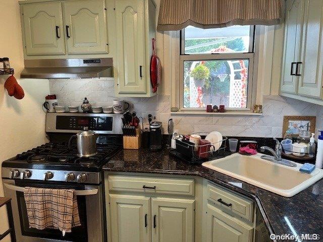 kitchen featuring tasteful backsplash, stainless steel gas range oven, sink, and dark stone counters