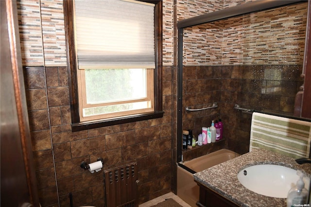 bathroom with tile walls, radiator, and combined bath / shower with glass door