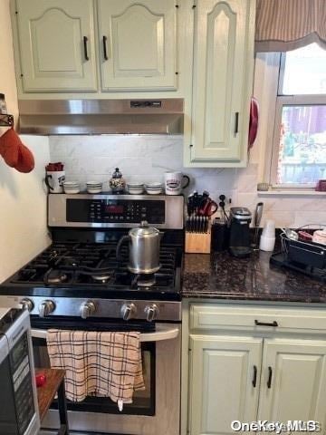 kitchen with tasteful backsplash, stainless steel gas range, and dark stone counters