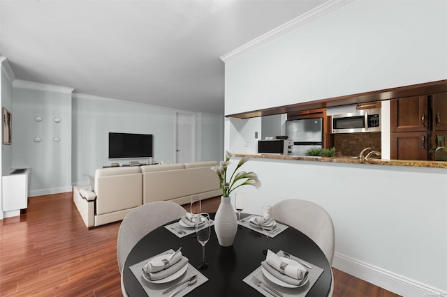 dining space with dark hardwood / wood-style flooring, ornamental molding, and sink