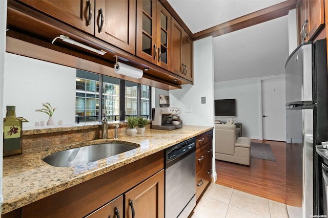 kitchen with light stone countertops, sink, light wood-type flooring, and appliances with stainless steel finishes