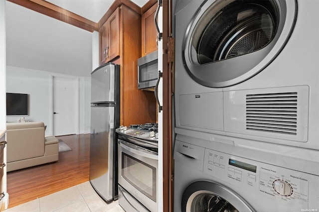 clothes washing area with stacked washer / dryer and light tile patterned flooring