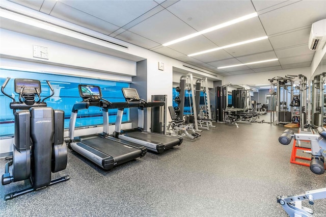 gym with a wall unit AC and a drop ceiling