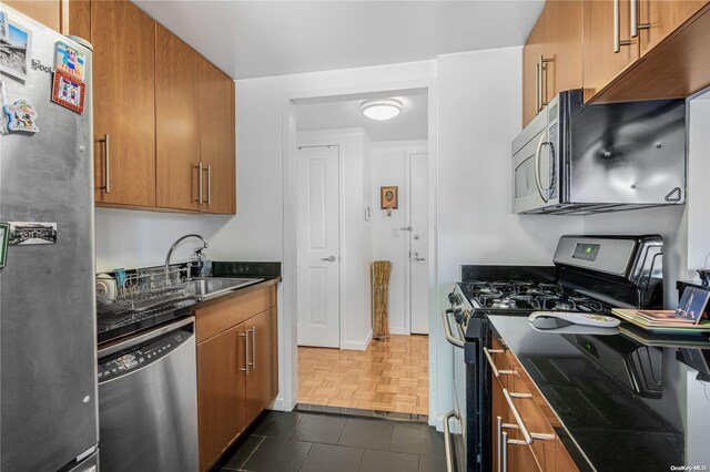 kitchen with dark parquet flooring, stainless steel appliances, and sink