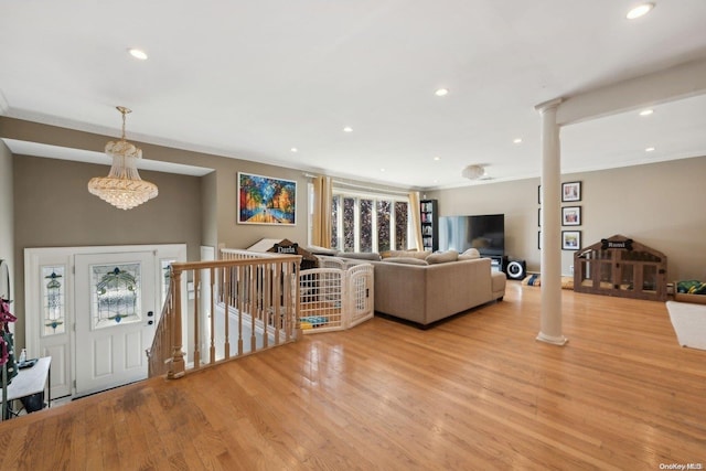 living room with a notable chandelier, ornamental molding, and light hardwood / wood-style flooring