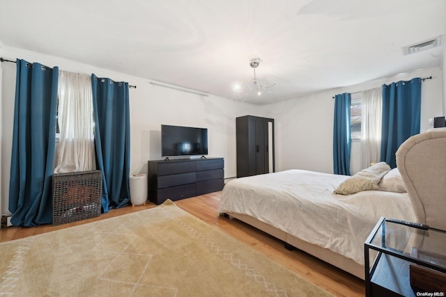 bedroom with light hardwood / wood-style flooring and a notable chandelier