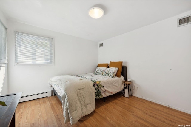 bedroom with wood-type flooring and a baseboard radiator