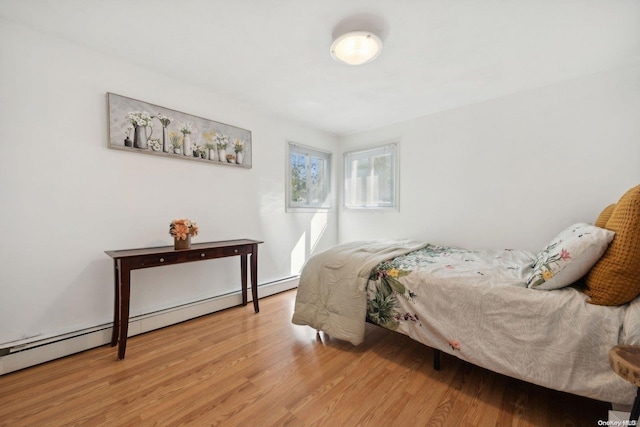 bedroom with baseboard heating and light hardwood / wood-style flooring