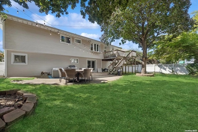 rear view of property featuring a lawn, a wooden deck, and a patio