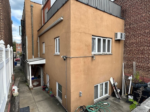 view of side of property featuring a patio and an AC wall unit