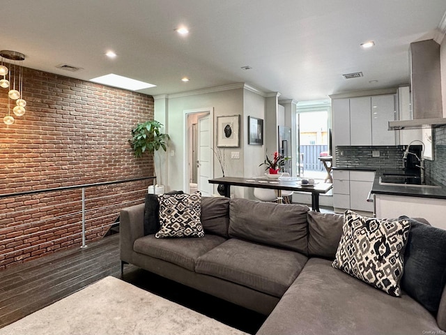 living room with crown molding, brick wall, sink, and dark hardwood / wood-style floors