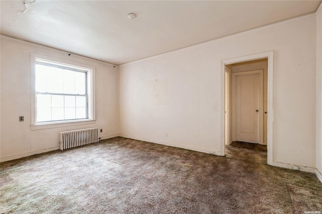 spare room featuring radiator and dark colored carpet