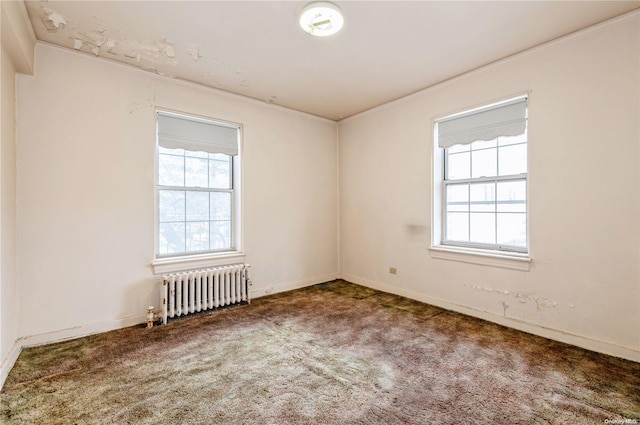 carpeted spare room with plenty of natural light and radiator heating unit