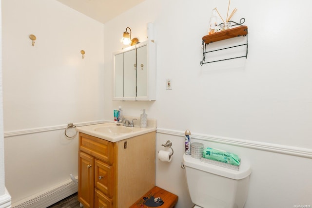 bathroom with wood-type flooring, vanity, a baseboard radiator, and toilet