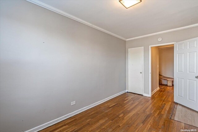 spare room with ornamental molding and dark wood-type flooring