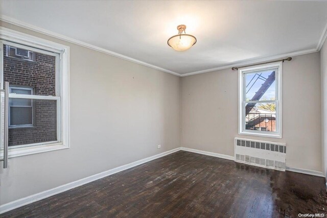 empty room featuring crown molding, radiator heating unit, and dark hardwood / wood-style floors