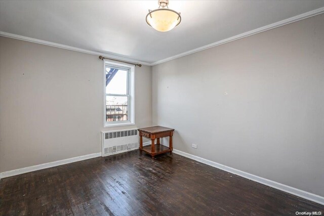 spare room with crown molding, radiator heating unit, and dark hardwood / wood-style floors