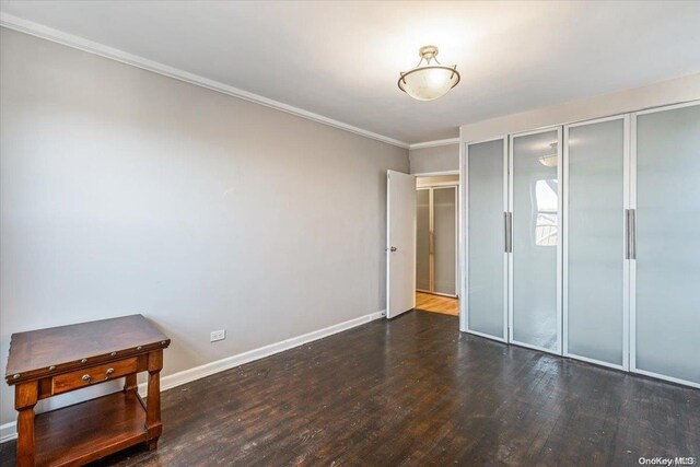 unfurnished bedroom with ornamental molding and dark wood-type flooring