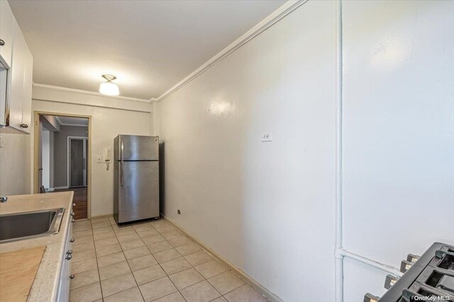 kitchen with stainless steel fridge, crown molding, sink, and light tile patterned flooring