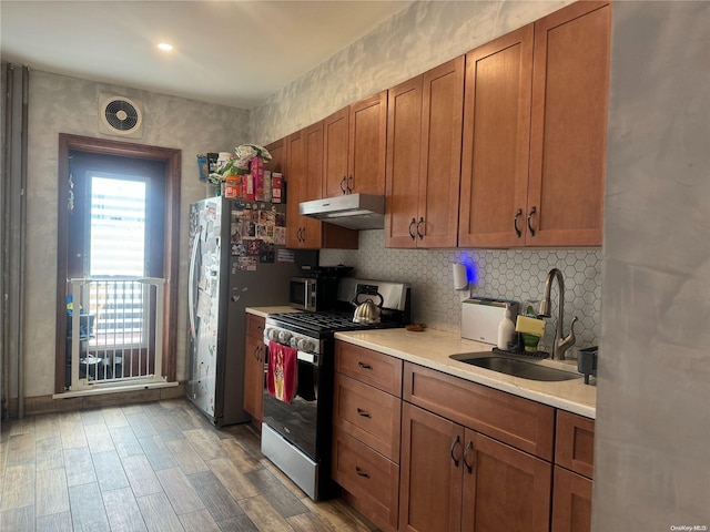 kitchen featuring stainless steel gas range oven, sink, and light hardwood / wood-style floors