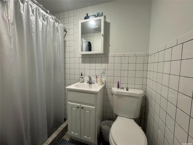 bathroom featuring vanity, toilet, tile walls, and walk in shower