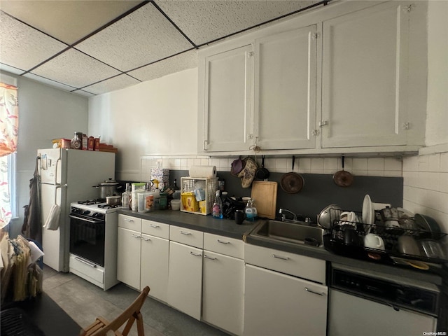 kitchen featuring a paneled ceiling, white appliances, sink, tasteful backsplash, and white cabinetry