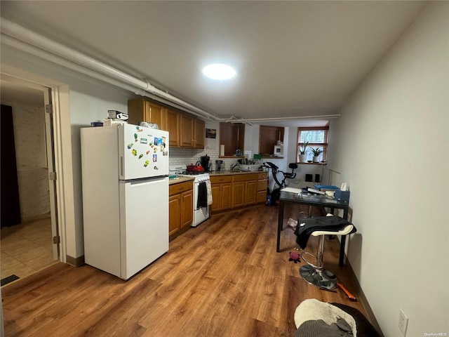 kitchen featuring hardwood / wood-style flooring, white appliances, and tasteful backsplash