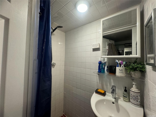 bathroom with a shower, sink, and tile walls