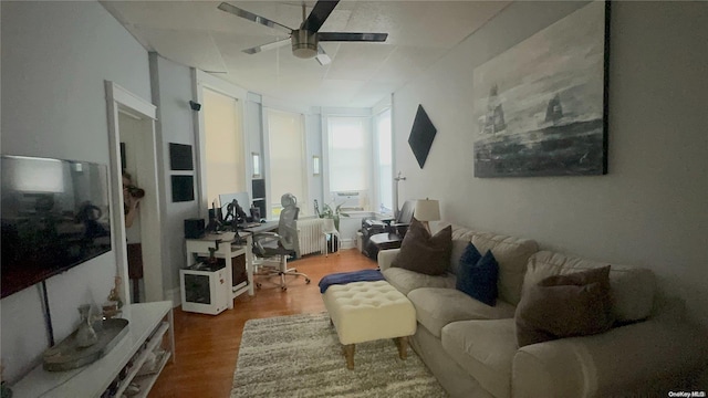 living room featuring hardwood / wood-style flooring, ceiling fan, and radiator heating unit