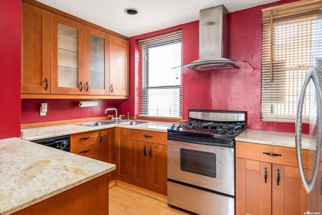 kitchen featuring light stone countertops, light wood-type flooring, gas range, extractor fan, and sink