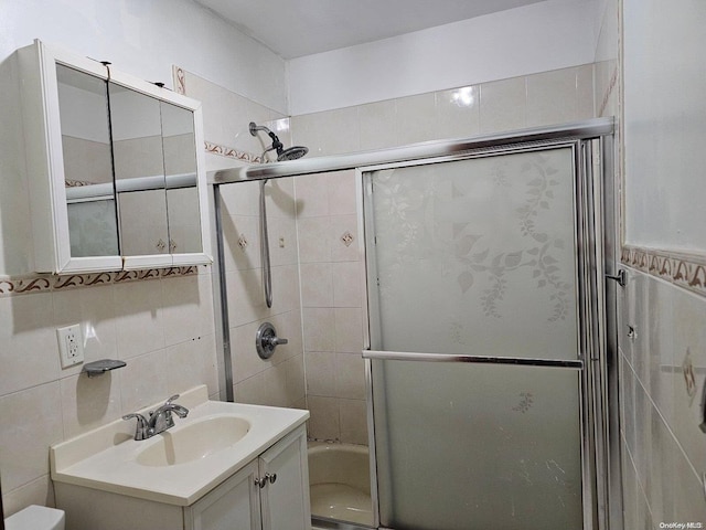 full bathroom featuring vanity, toilet, shower / bath combination with glass door, and tile walls