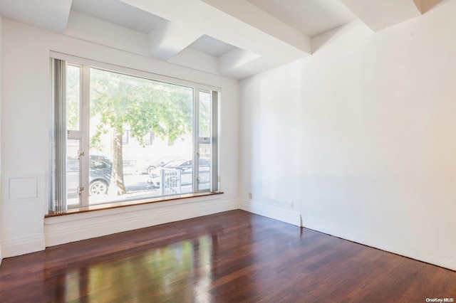 empty room featuring beam ceiling and dark wood-type flooring