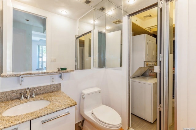 bathroom with tile patterned floors, stacked washer and dryer, vanity, and toilet