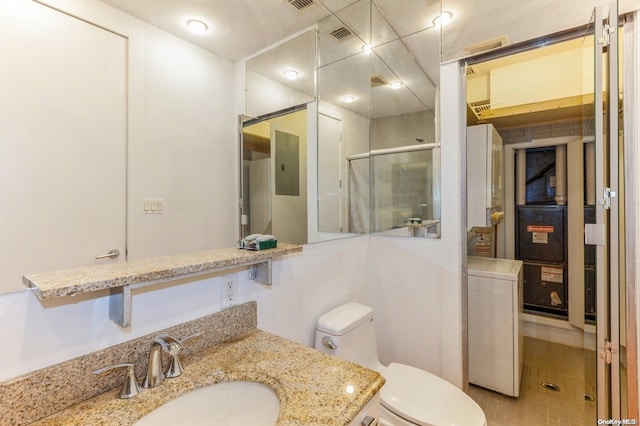 bathroom featuring toilet, vanity, tile patterned floors, and a shower with shower door