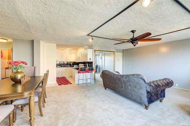 carpeted living room featuring ceiling fan and a textured ceiling