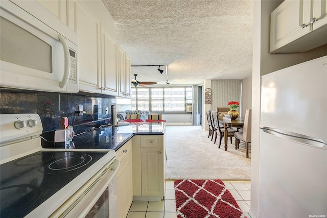 kitchen with a textured ceiling, white appliances, track lighting, and light tile patterned flooring