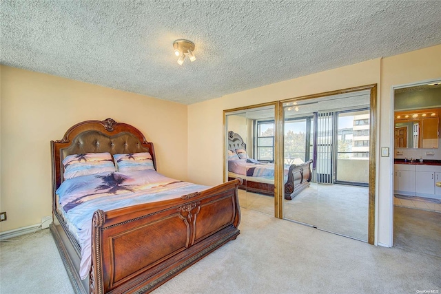 carpeted bedroom featuring ensuite bathroom, a closet, and a textured ceiling